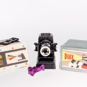 DIAX II - různé verze obchodních balení. Promítačka byla v krabici většinou zabalena ve fialovém tzv. "hedvábném" papíru.